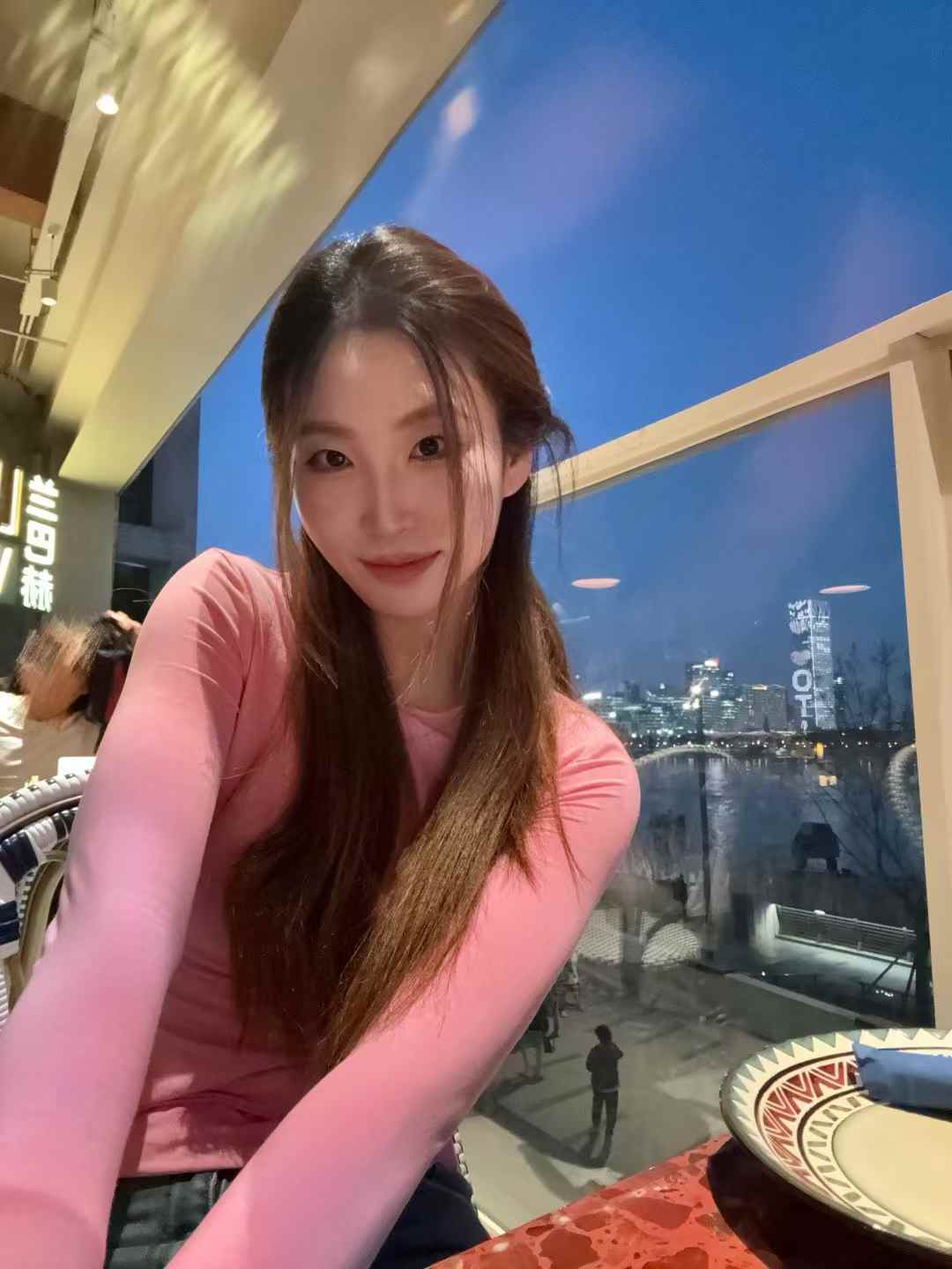 Source image for Woman in Pink Leaning Forward at Riverside Restaurant at Night