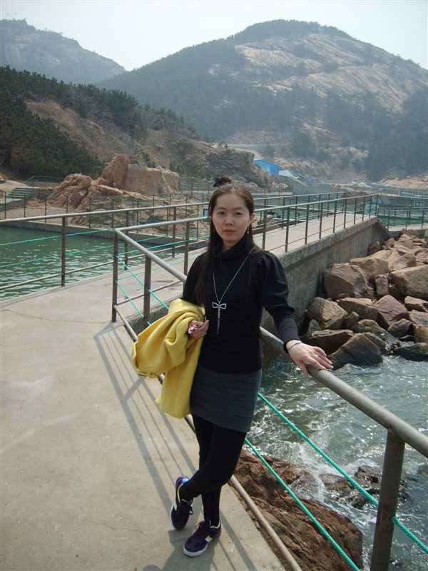 Source image for Woman in Black Leaning on Railing at Rocky Coastal Park