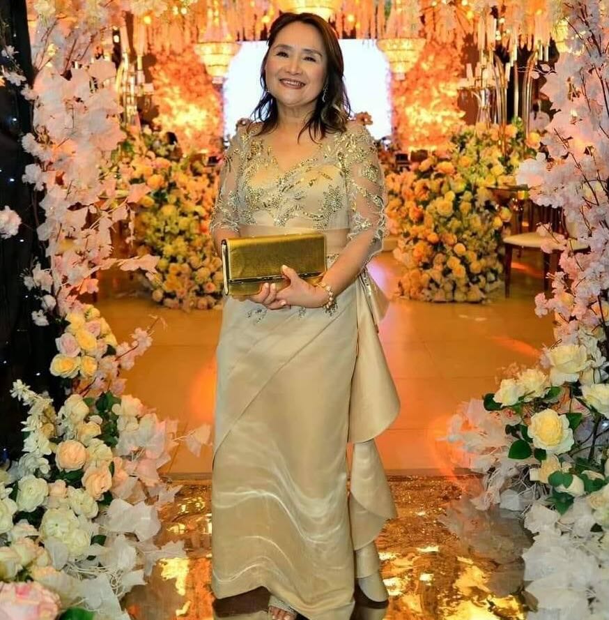 Source image for Elegant Woman Removes Gold Clutch and Faces Forward at Floral Event